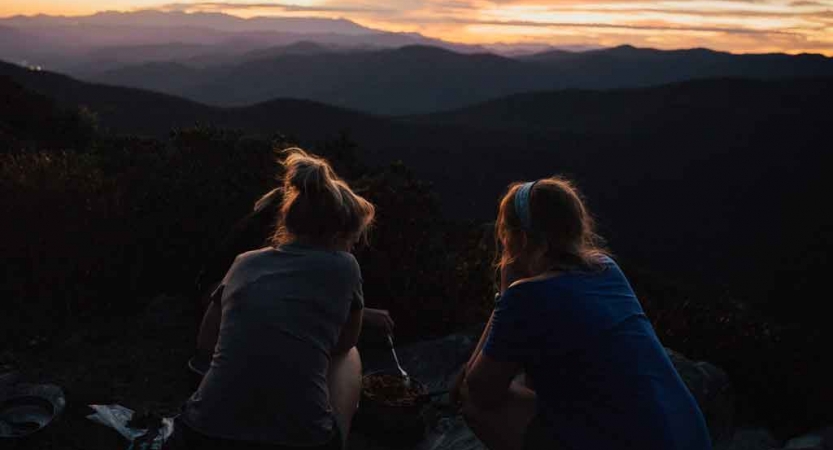 two students sit on an overlook of the blue ridge mountains on an outward bound expedition 